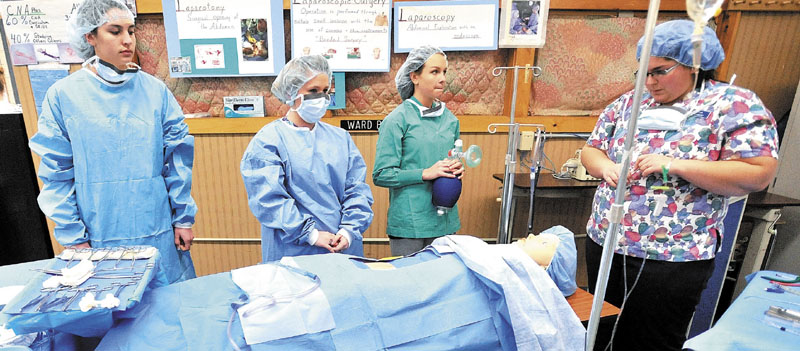 MEDICAL ARTS: From left to right, Sarah Emerson, Picabo Morrell, Crystal DeCosta, and Tanisha Kitchin demonstrate a surgical procedure for parents and students during the skills showcase at the Somerset Career & Technical Center in Skowhegan on Wednesday.