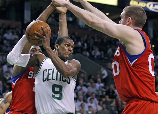 Boston Celtics guard Rajon Rondo (9) looks to pass against the defense of Philadelphia 76ers forward Thaddeus Young, left, and center Spencer Hawes, right, during the Celtics' 99-82 win Tuesday in Boston.