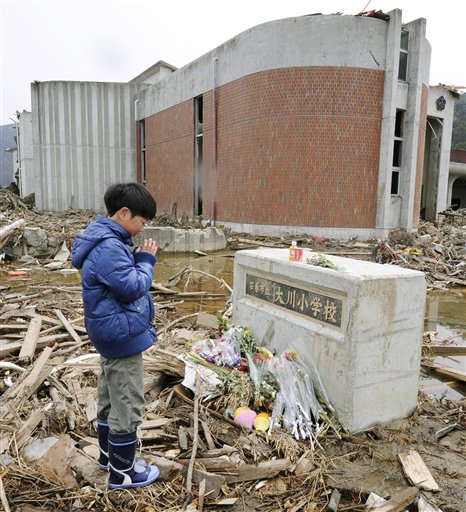 A Japanese student prays for victims at an elementary school in Ishinomaki, northeastern Japan, on Monday April 11, 2011. Exactly a month ago a massive earthquake and tsunami ravaged Japan's northeastern coastal region.
