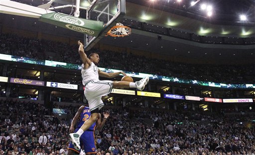 Boston Celtics guard Avery Bradley, top, follows through on a slam dunk after beating New York Knicks guard Anthony Carter on a fast break during the first quarter Wednesday in Boston.
