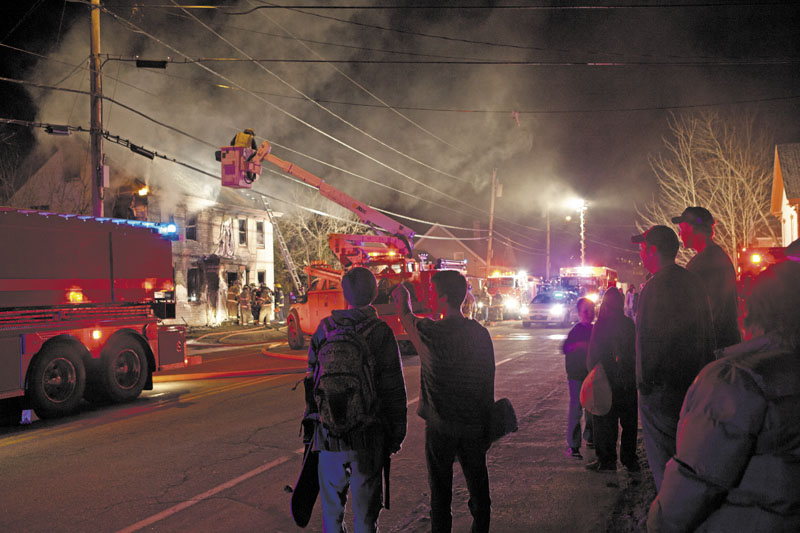 Bystanders watch firefighters attempt to douse a fire in Randolph Saturday night. The fire restarted Sunday morning. Officials suspect the fire was set.