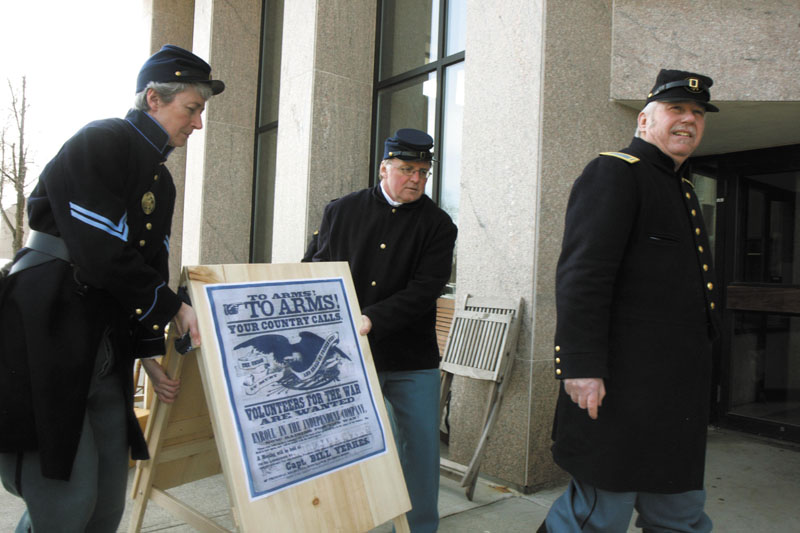 Darlene Coltart, left, and David Wylie, of Company B, 20th Maine Regiment, work together to place a sign outside the Maine State Museum during a "recruiting drive" re-enactment on Saturday in Augusta to commemorate the start of the Civil War. Far right is Paul Dudley, president of Company B, 20th Maine Regiment.