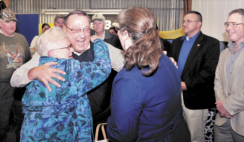 Gov. Paul LePage gets a hug from Ursala LePage, no relation, of Knox, as Mary Anne Kinney gave him a basket of maple products during the 51st annual open house at Ingraham Equipment in Knox on Wednesday. LePage spoke with area farmers and said the state will become pro business and not an adversary to growth that has made farming an "endangered species." LePage further cited the newspaper industry as struggling and said," I"m doing my part to sell papers." At right is Commissioner of Agriculture Walter Whitcomb.