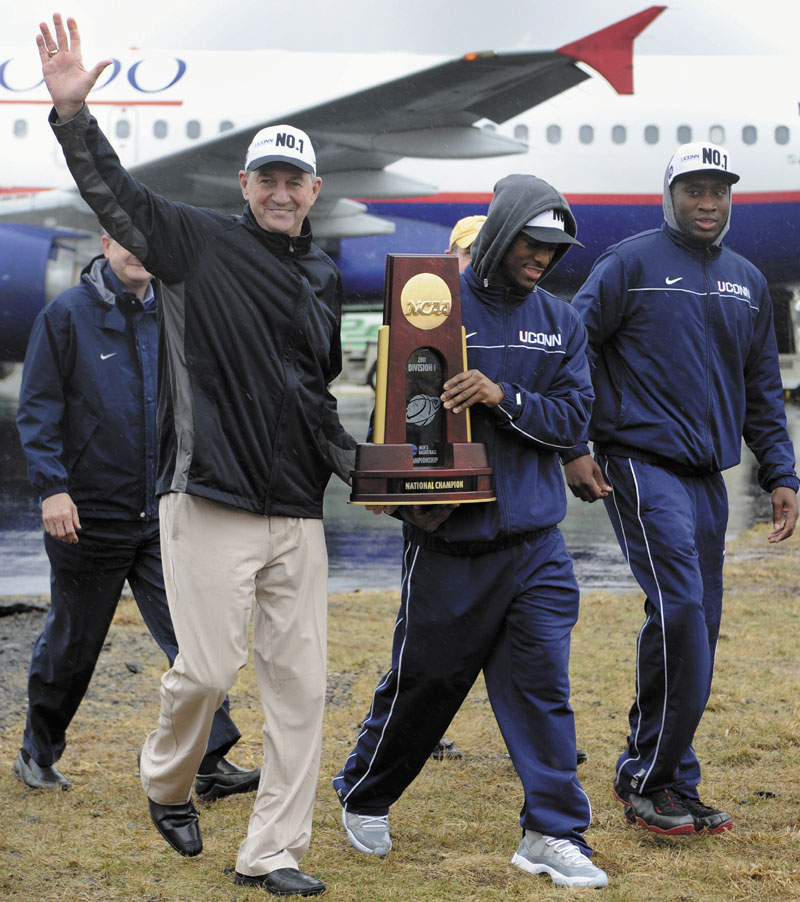 LOOK OF A CHAMP: Connecticut head coach Jim Calhoun, left, and senior Kemba Walker carry the championship trophy as they arrive for a rally Tuesday at Bradley International Airport in Windsor Locks, Conn.