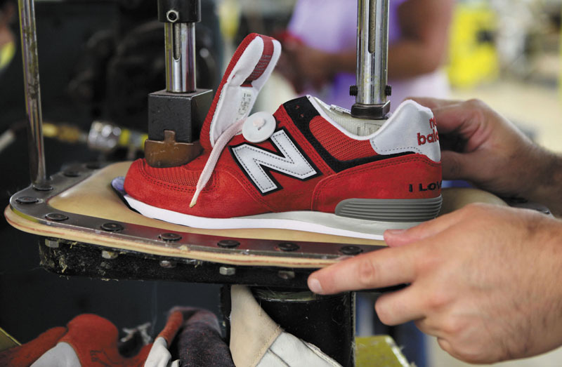 LOCAL JOBS: A worker uses a press to attach a shoe upper to the outsole at the New Balance factory in Norridgewock. The Obama administration is negotiating a free-trade agreement with Vietnam and seven other countries, and it is unclear whether the New Balance plant can stand up to a flood of shoes from that country
