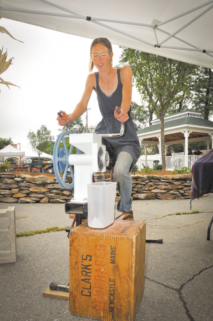 PEDALING: Johanna Davis of Songbird Farm in Starks demonstrates a bike-powered grain mill at the bread fair on Saturday.