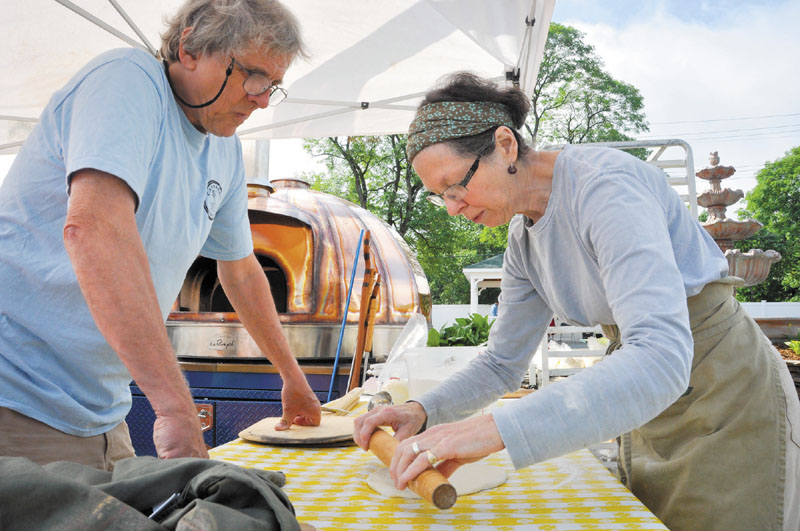 ALSO COOKING: Mark Roman and MaryAnn Reynolds, both of Solon, prepare some pizza dough for the wood-fired baking oven shown in the background at Saturday’s Artisan Bread Fair in Skowhegan.