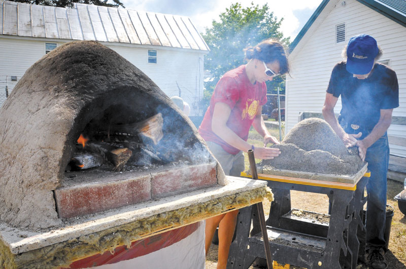 COOKING: Polly MacMichael of New Portland and Stuart Silverstein of Waterville build a practice-size baking oven at Saturday’s 2011 Artisan Bread Fair at the Skowhegan State Fairgrounds. These small ovens can be used for small flatbreads and can be built larger to accommodate the baking of larger breads.
