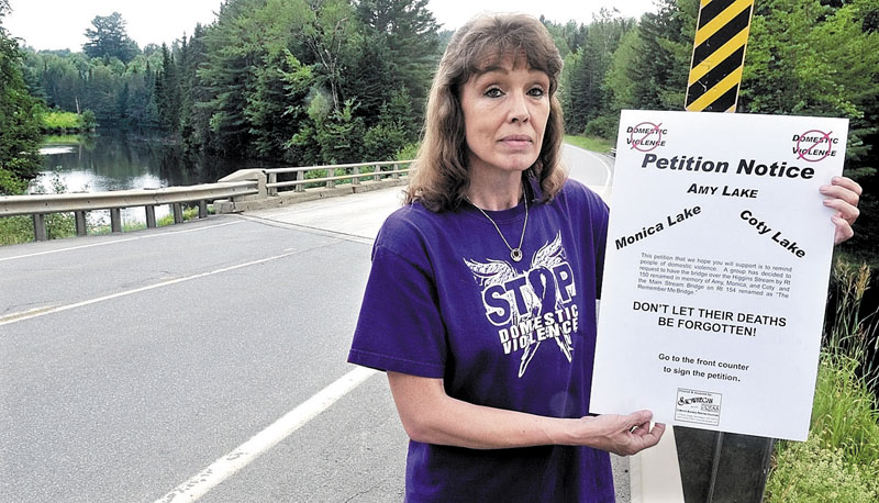 AN EFFORT TO END VIOLENCE: Sandra Mitchell holds a petition while standing on the Higgins Stream Bridge in Harmony on Tuesday. The petition calls for renaming the bridge in memory of schoolteacher Amy Bagley Lake and her children Monica and Coty, who were killed in Dexter last month. Another nearby bridge would be renamed to bring awareness to domestic violence issues.