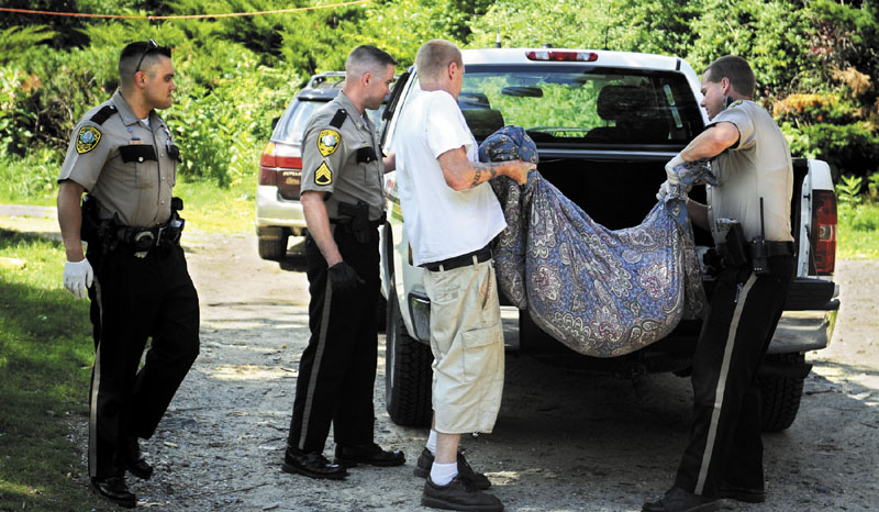 ALL THAT REMAINS: Kennebec County Sheriff's Deputy Joshua Hardy, right, loads the remains of a dog belonging to Jeremiah Bailie, second from right, Wednesday at his home in Manchester.