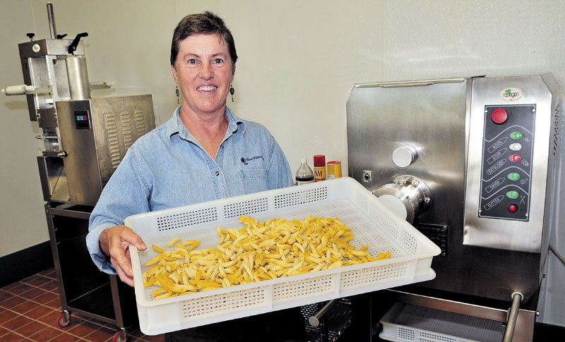 FRESH: Standing in front of pasta- and ravioli-making equipment, Mary Burr holds a tray of penne she and her husband, Bob, made at their Pasta Fresca business at Blue Ribbon Farm in Mercer. The couple will use local grains that will be milled at the grist mill in Skowhegan to make their pasta.