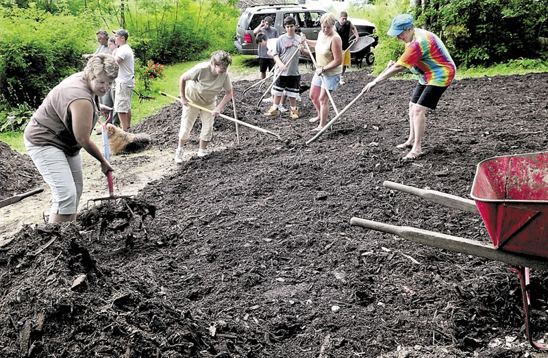 SLOWING EROSION: In an effort to slow erosion and reduce algae blooms, homeowners, campers and members of the Youth Conservation Corp. spread mulch on a hillside at the Wood Haven trust cottage on Pattee Pond in Winslow. Owners and sisters from left are Whendy Smith, Linda Daigle, Kim MacKay and Carolyn Albert.