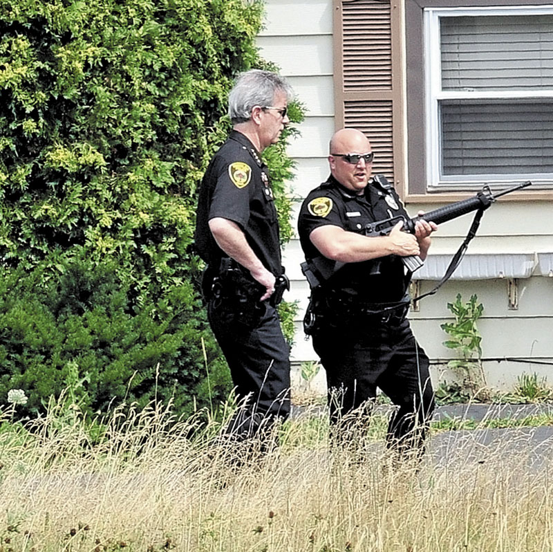 STANDOFF: Winslow Police Chief Jeffrey Fenlason, left, and officer Joshua Veilleux and other police search for a man in Benton on Monday. As of Monday evening, the man had not been found.