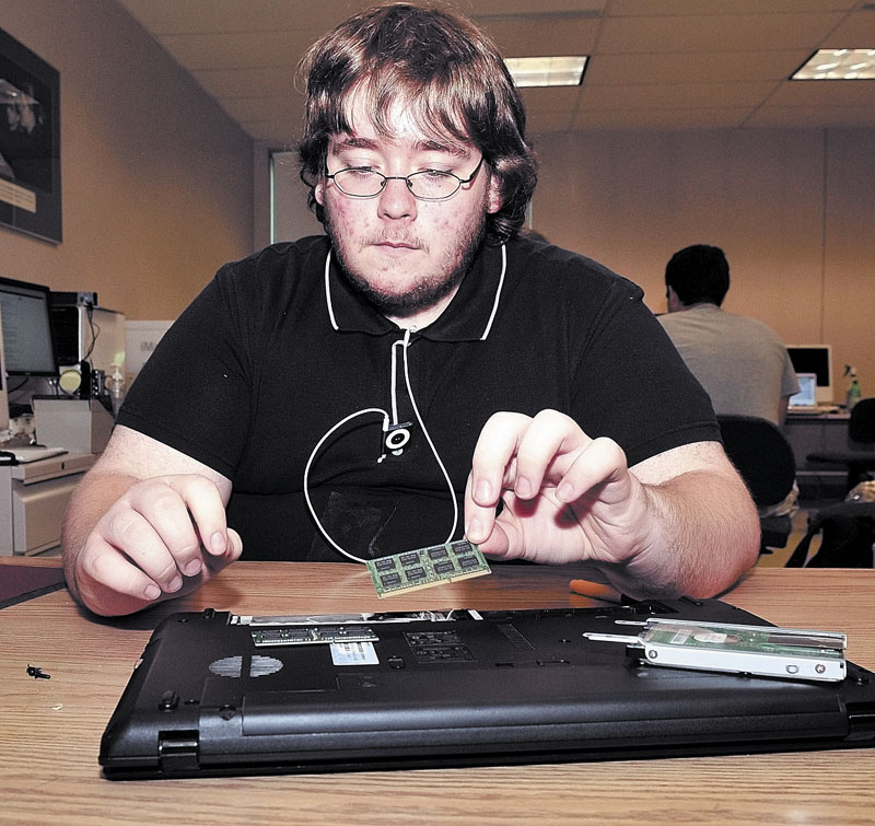 HIGH-TECH: Andrew Leonard of Waterville removes the hard drive and other components of a computer during a program at the University of Maine at Farmington. Students are getting a chance to take classes, work part-time jobs and stay on a college campus as part of the Upward Bound summer program.