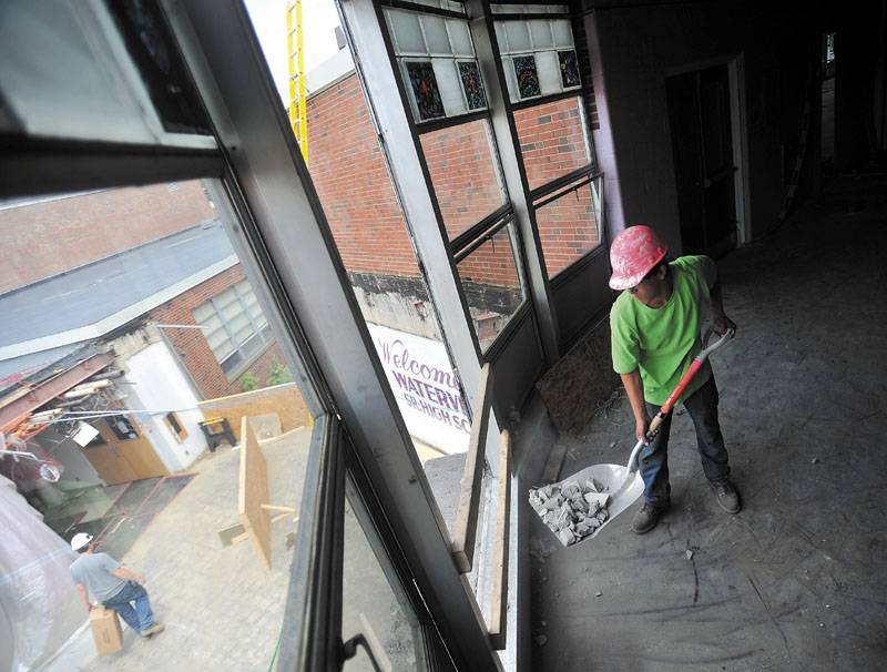 WORKING: Taddy Bibeault, 18, a laborer with SMS Demolition, clears refuse from the second story of Waterville Senior High School during renovations on Friday. Workers are finishing the second week of the three-week phase of remodeling the school.