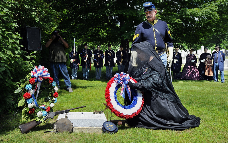 Carolyn Lawson, a member of the Auxillary of the Union Veterans of the Civil War, lays a wreath at the new headstone of the grave of Private William Johnson, a Union soldier in the Civil War, with the assistance of Mike Nugent of the 1st Cavalry reenactors during a special ceremony today marking the newly confirmed grave of Civil War Private William Johnson at Baptist Cemetery, Yarmouth. In back are the 3rd Maine Infantry reenactors and related character reenactos of the Civil War era.
