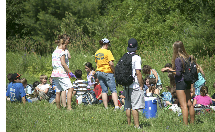 School bus passengers wait in the grass after the accident on I-295. The RSU 5 bus was carrying 30 children and six staff members who were returning from a field trip in Portland.