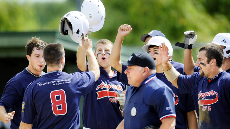 RALLY: Augusta’s Corey Lapierre celebrates with teammates at home plate after hitting a home run against Brewer during the American Legion baseball state tournament Wednesday in Augusta. Augusta beat Brewer 16-4 in a game shortened to seven innings by the 10-run rule.