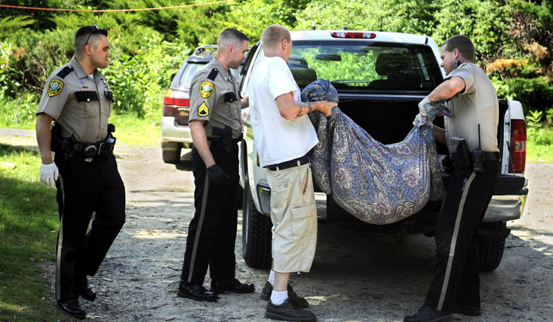 ALL THAT REMAINS: Kennebec County Sheriffs Deputy Joshua Hardy, right, loads the remains of a dog belonging to Jeremiah Bailie, second from right, Wednesday at his residence in Manchester after the dog attacked his mother-in-law, Lena Walker, 68, and his 11-year-old son. Another son, 12, shot the dog.