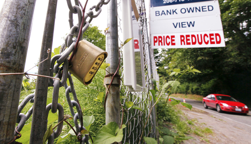A "bank-owned" lot is chained and locked but advertised for sale in Seattle in this June 9 photo.