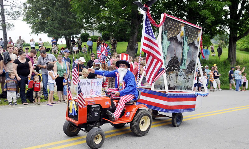 OUT IN FRONT: A lawnmower towing a trailer leads the Fourth of July parade Monday through Kings Mills in Whitefield. The annual celebration draws hundreds to watch and participate in the pageantry and patriotism.