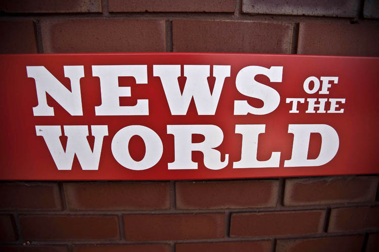 News of the World sign is seen by an entrance at premises of News International in London. James Murdoch, News Corporation executive says the News of the World will publish its last issue on Sunday. The focus of the phone hacking scandal shifted today to serious allegations of police corruption as Scotland Yard called for an independent review of reported payoffs by journalists to police.