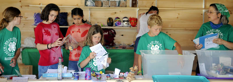 COME ONE, COME ALL: Members of Bluebird 4-H Club, of Benton, set up items for display Tuesday in the new Exhibition Hall at the Pittston Fair. The annual agricultural fair starts Thursday and ends Sunday.