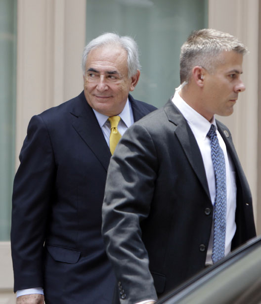 Former IMF head Dominique Strauss-Kahn, left, leaves his rented house escorted by security today in New York.