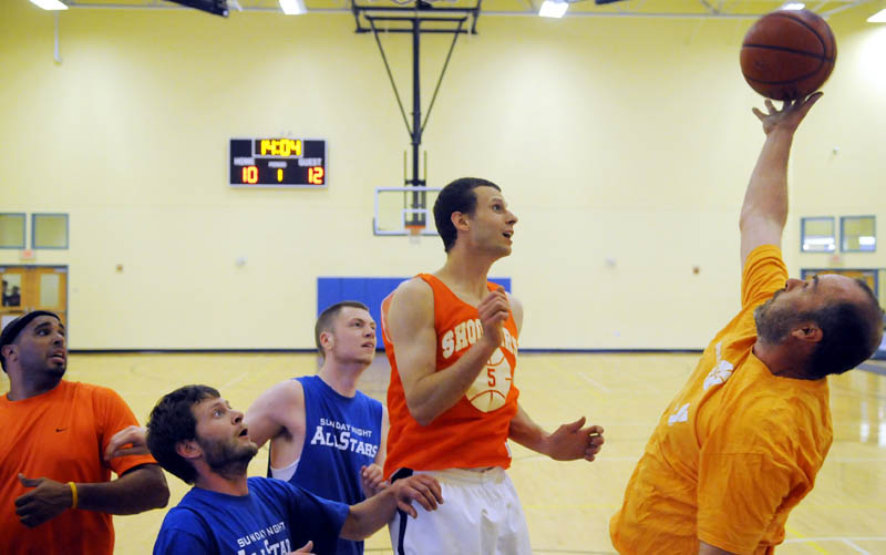 STILL LOVE THE GAME: Crew team member Dave Howe, right, reaches for a rebound in a Kennebec Valley YMCA men’s league game against the Sunday Night All Stars on Wednesday in Augusta. The league has six teams, many with former high school and college stars from the area.
