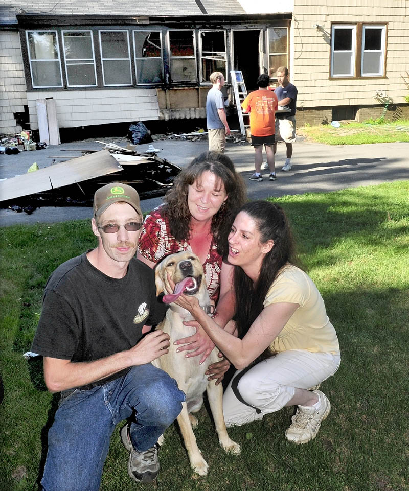 Neighbors Randy LaPointe, Betsy Abbott and Debra Kilsby crowd around dog Abby Doodle, who they rescued last Saturday after fire erupted on the porch of a home in Waterville. People for the Ethical Treatment of Animals is giving the three rescuers its Compassionate Action Award. In background, homeowners Chris and Heather Stone speak with contractor Sheldon Skidgel, right.