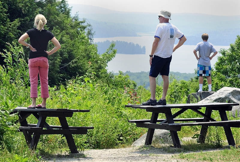 Jen Porter, left, and Mike Riley and Jack Hubley take in the views of the Belgrade Lakes through the haze from high atop Blueberry Hill this week in Rome. Temperatures are again likely to near 100 today, but Sunday should offer a reprieve.