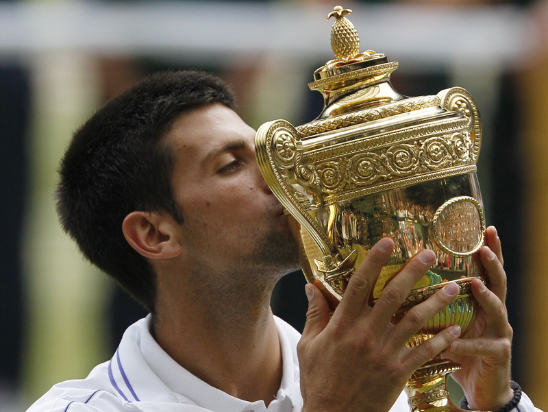 Novak Djokovic kisses the trophy after defeating Rafael Nadal in the men's singles final at the All England Lawn Tennis Championships at Wimbledon today.