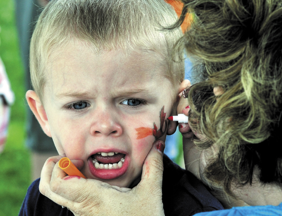 Staff photo by David Leaming ROAR: Mack Merrow looks a little nervous as Bobbi Estes paints a dragon on his face during the Central Maine Egg Festival Egglypics games at Hathorn Park in Pittsfield on Wednesday.