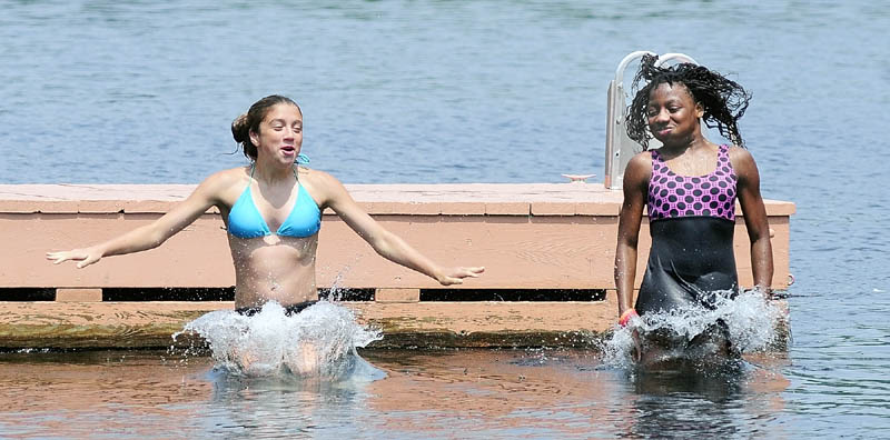 Kianna Pushard, left, and Idasia Santos jump into Lower Narrows Pond on Tuesday afternoon at More To Life Campground in East Winthrop. Santos, of the Bronx, NY, is staying with the Pushard family as part of the Fresh Air Fund program.