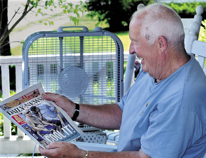 NO FAN OF HEAT: Walter Frame cools off with an electric fan blowing while reading the New York Daily News on his porch in Waterville on a hot and muggy Friday. Not surprisingly, the metro newspaper ran a photo of two men also cooling off with a fan as hot weather scorches the East Coast. More heat is expected today.