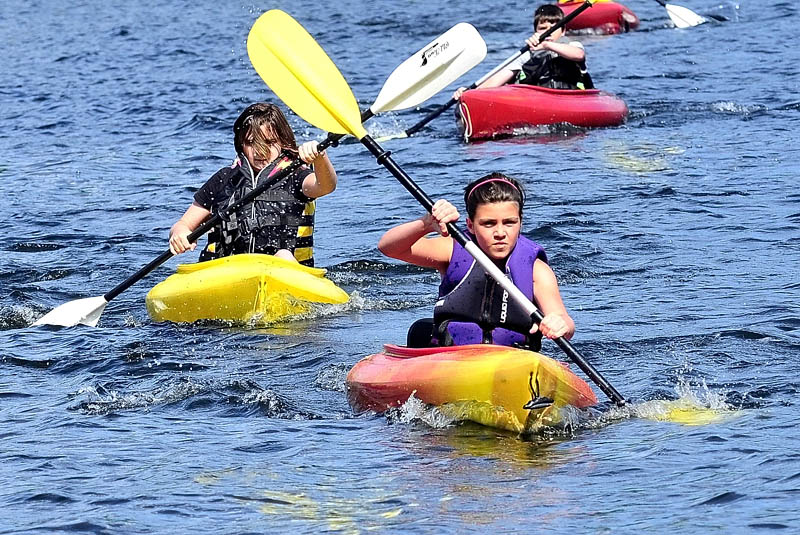 During Camp Loon Survivor Island events on Friday, Katie Guarino leads Elizabeth Newman and Nick Veilleux in a kayak race on Great Pond beside the Belgrade Community Center for All Seasons.