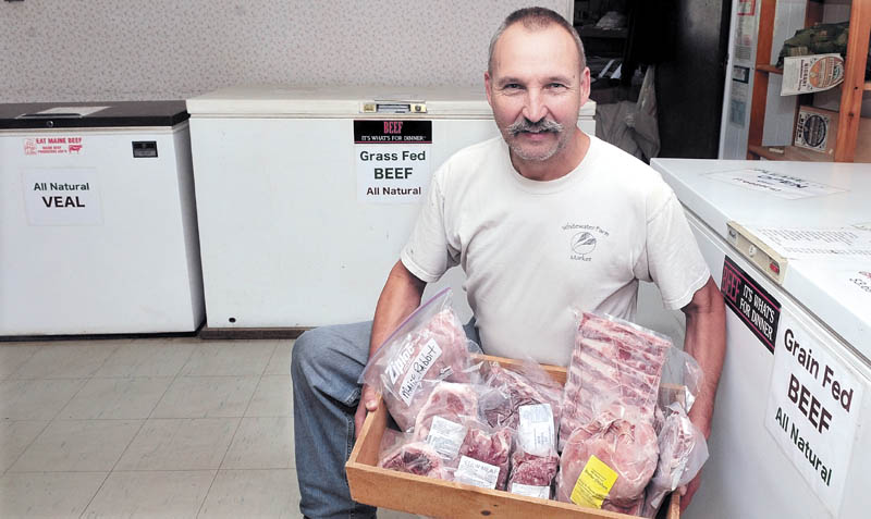 LOCAL: Russell Dodge holds a tray of various locally raised meats at his Whitewater Farm Market in New Sharon. Al and Dianne Keene are collecting recipes for a cookbook that promotes natural and local products that will benefit consumers, producers and retailers.