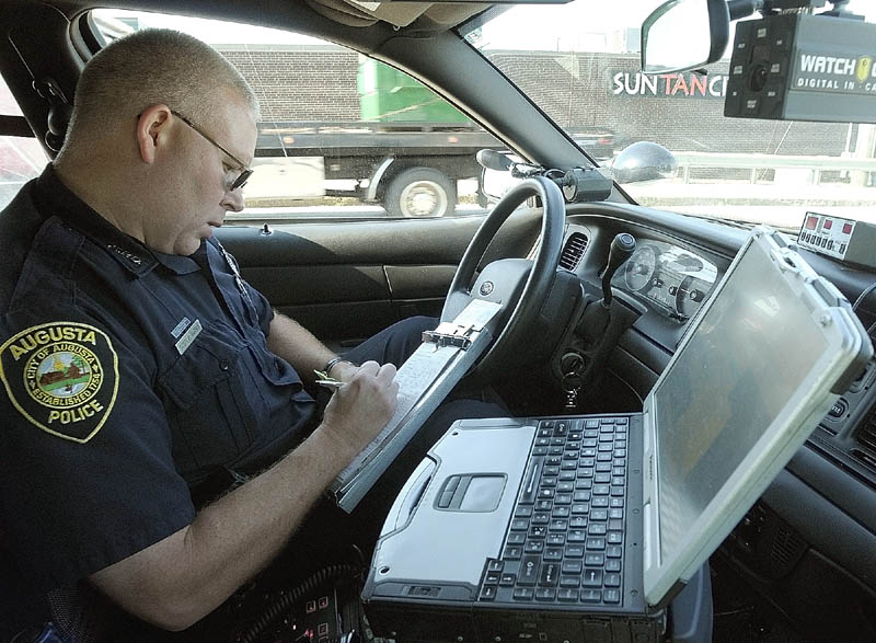 Augusta Police Officer Scott P. Harris writes up a ticket during a speeding enforcement detail Friday morning on Western Avenue in Augusta. He used the computer in the cruiser to check the driver's records.