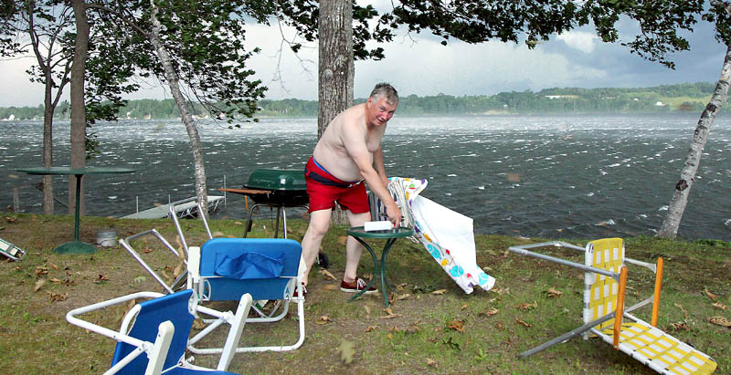 Phil Norvish of Waterville tries to gather up lawn furniture at his camp on China Lake as white caps whip across the water during Wednesday evening's storm.
