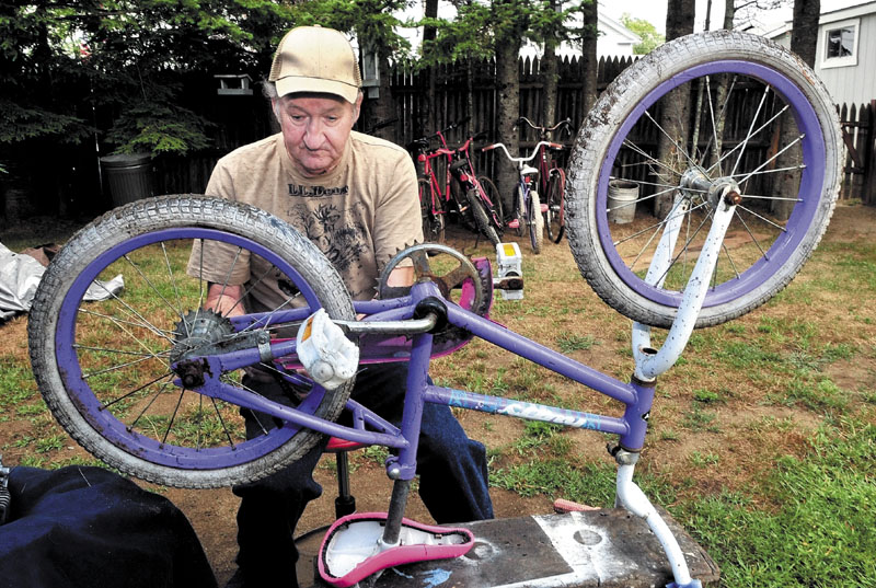 FIXER-UPPER: Hugh Breingan, 70, fixes a bicycle that will be given away to an area child at his home in Skowhegan. The bicycles in the background are finished and waiting for new owners.