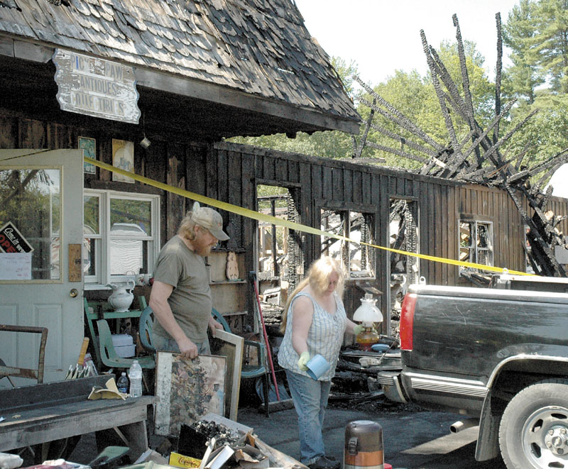 DAMAGE: Rick and Lynn Doane remove what they can on Monday from Pick & Paws Collectibles on U.S> Route 2 in Mercer after fire destroyed the building Saturday night.