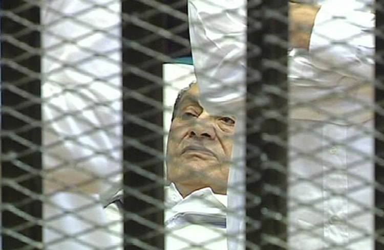 This video image taken from Egyptian State Television shows 83-year-old former Egyptian president Hosni Mubarak lying on a hospital bed flanked by his two sons Gamal and Alaa, inside a cage of mesh and iron bars in a Cairo courtroom today.