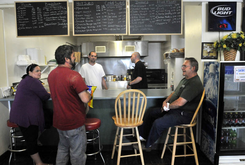 Brenda DiMeo, far left, and her sons Jeremy, back center in white shirt, and Tony, back center, owners of the Cambridge General Store in Cambridge share a luagh with local customers on Friday. Cambridge General Store is the only retail outlet in Cambridge.