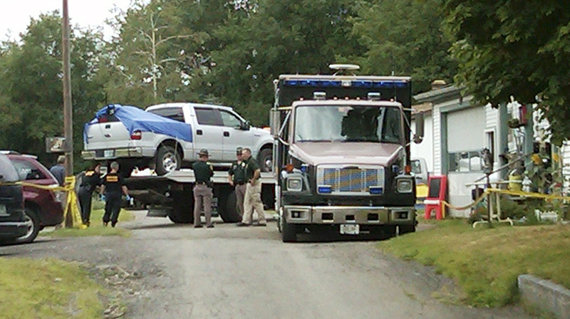 This cell phone photo shows law enforcement officials standing near a silver pickup truck being removed from where it was parked near the home of Celina Cass, in Stewartstown, N.H., today.