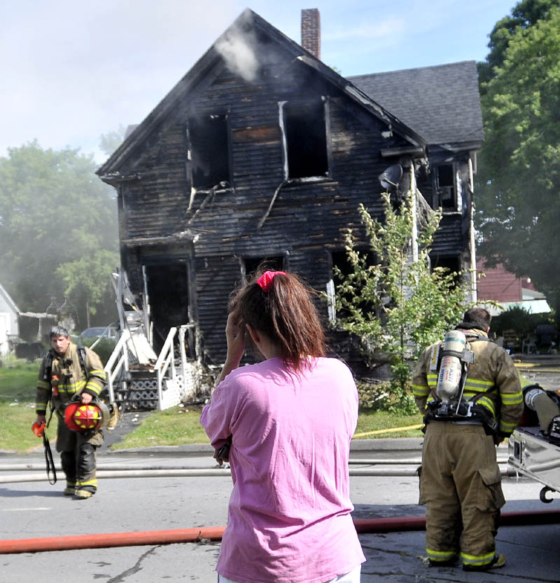 Tracey Bragdon stands in front of her Oak Street home in Waterville on Tuesday as firefighters battle the blaze.