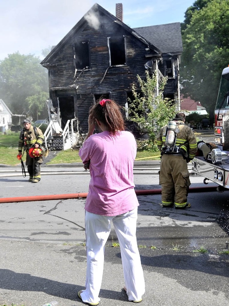 Staff photo by Michael G. Seamans Tracy Bragdon stands in front of her Oak Street home in Waterville, Tuesday morning, as Forty firefighters from four agencies including, Waterville, Winslow, Fairfield and Oakland Fire Departments, battle the blaze. No injuries were reported.