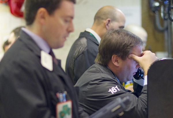 Traders work on the floor of the New York Stock Exchange today. All three major stock indexes are down 10 percent or more from their previous highs, a drop-off that is considered to be a market correction.
