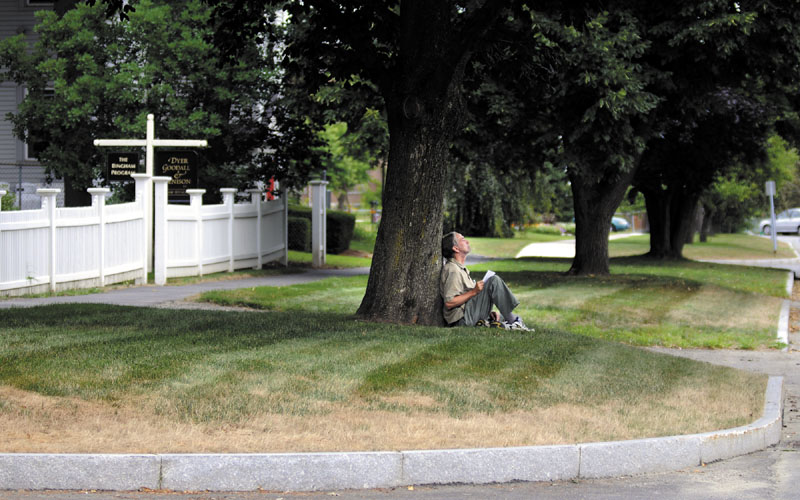 WIDE OPEN SPACES: John Taber, of Farmingdale, waits for a ride Wednesday beneath a tree on the esplanade between the sidewalk and Winthrop Street in Augusta. In some spots, there’s nearly 25 feet of space between the sidewalk and street. The city-owned property will be the subject of a council discussion Thursday.
