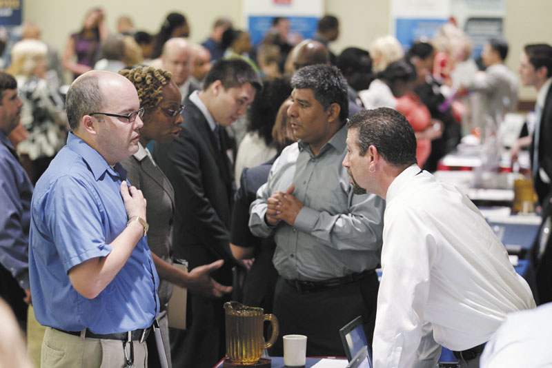Jjob seeker Manfred A. Lynch, left, speaks Thursday with a recruiter at a job fair in Arlington, Va. The Labor Department announced Friday that hiring picked up slightly in July and the unemployment rate dipped to 9.1 percent as employers added 117,000 jobs.
