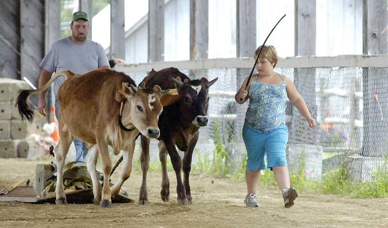 Dionica Robinson walks beside Ace and Edgar as she competes in the farmers pull on Thursday morning at the Monmouth Fairgrounds on Academy Road in Monmouth. The fair runs through Saturday.